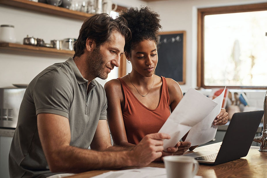 Our debt is almost paid off. Cropped shot of a couple using their laptop and going through paperwork at home.